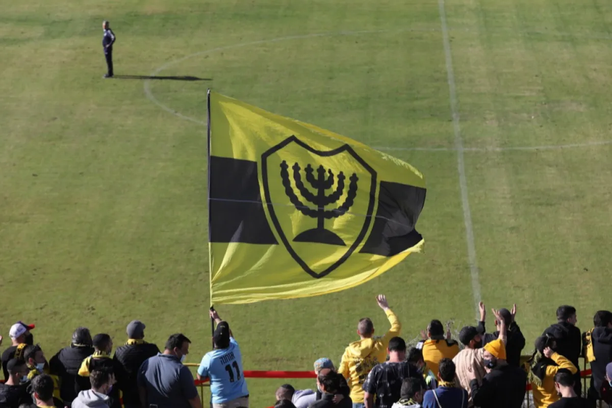 Fanii clubului de fotbal Beitar Jerusalem care susțin achiziționarea echipei de către un membru al familiei regale din Emiratele Arabe Unite aplaudă în timpul unei sesiuni de antrenament la Ierusalim, Israel, 11 decembrie 2020. Două grupuri de suporteri au protestat în timpul sesiunii de antrenament de la Beitar Jerusalem din 11 decembrie, unul susținând achiziția clubului de un membru al familiei regale din Emiratele Arabe Unite Sheikh Hamad bin Khalifa Al Nahyan, iar celălalt împotriva înțelegerii. Sheikh Hamad a cumpărat 50 la sută din clubul de fotbal Beitar Jerusalem și va investi 300 de milioane de șekel israelian (92 de milioane de dolari SUA) în următorul deceniu în echipa care nu a semnat niciodată un jucător arab și grupul său de fani de extremă dreapta 'La Familia' este cunoscută pentru atitudinea sa anti-musulmană.