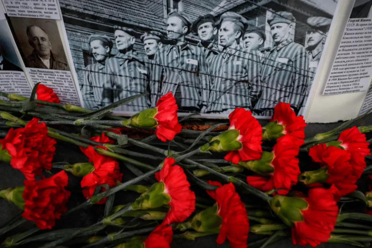 Flori în fața unei imagini cu deținuți, în timpul unei acțiuni comemorative pentru victimele lagărelor de represiune sovietice sub regimul lui Stalin, la Moscova, Rusia, 30 octombrie 2020.