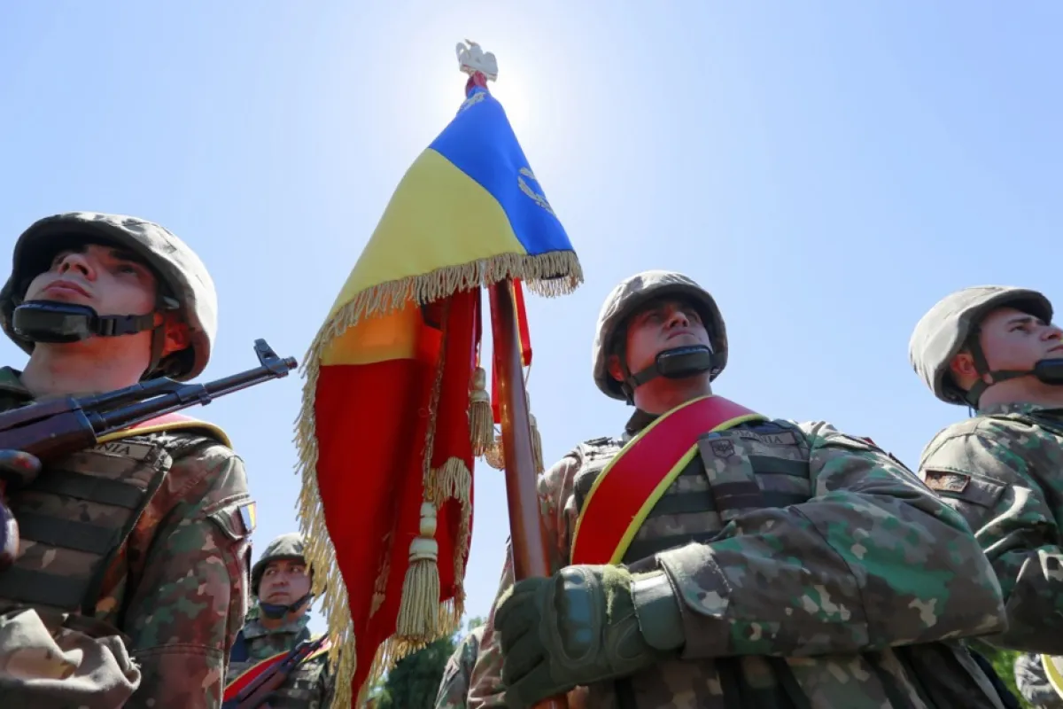 Militari români ținând drapelul de luptă al Batalionului 1 de Instrucție „Olt”, aparținând Armatei Române, în cadrul unei ceremonii în orașul Caracal, la 200 km vest de București, România, 19 mai 2022.