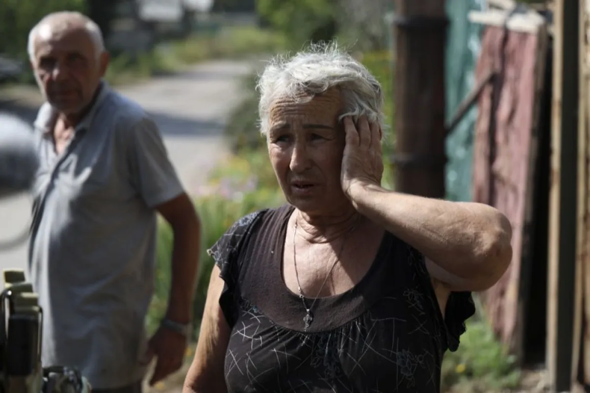 O femeie din localitate le spune polițiştilor despre casa ei recent bombardată în așezarea Avdiivka, lângă linia frontului din regiunea Donețk, Ucraina, 28 august 2023.