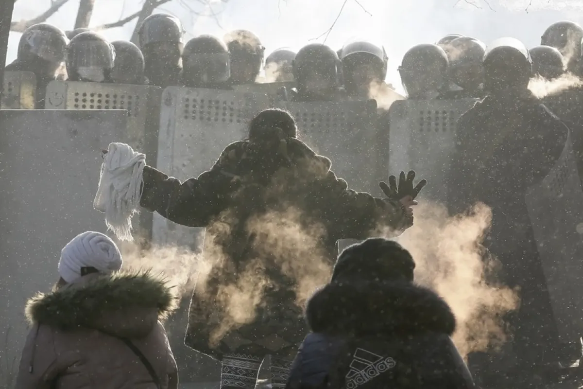 O ucraineancă îngenunchează în fața polițiștilor în timpul protestului antiguvernamental Euromaidan în centrul orașului Kiev, Ucraina, 25 ianuarie 2014.