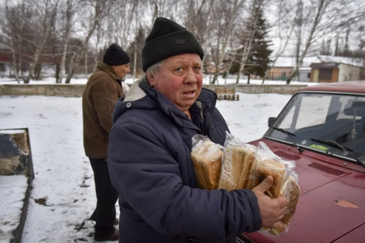 Un bărbat ține pâine distribuită de voluntarii administrației civile în Chasiv Yar, regiunea Donețk, estul Ucrainei, 25 februarie 2023, pe fondul invaziei Rusiei.